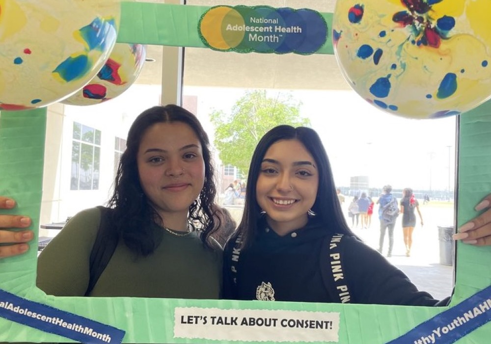 El Paso youth pose with a National Adolescent Health Month frame promoting consent education at a community event.